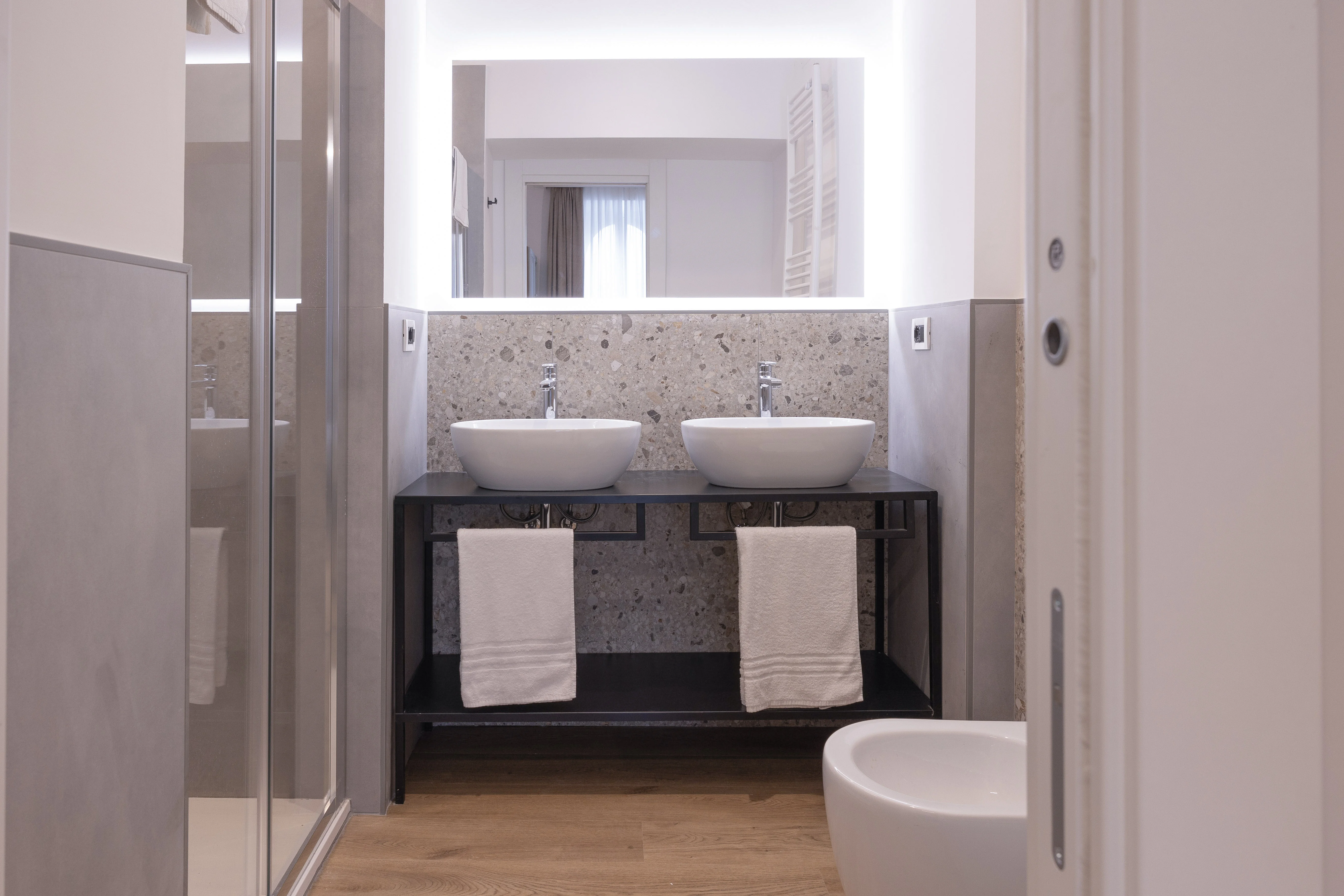 Bagno Camera King Suite - Tripla — doppio lavabo con rivestimento in terrazzo e specchio retroilluminato